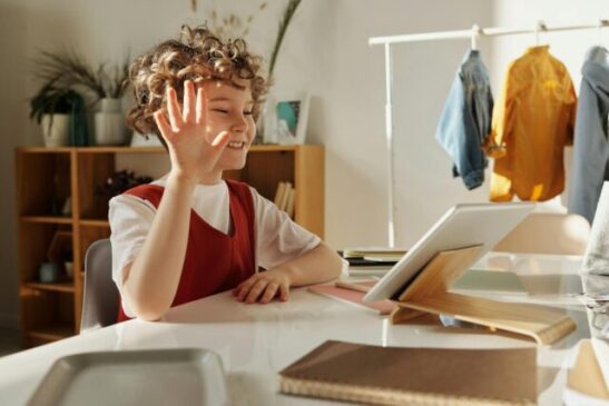 photo of child smiling while using tablet computer